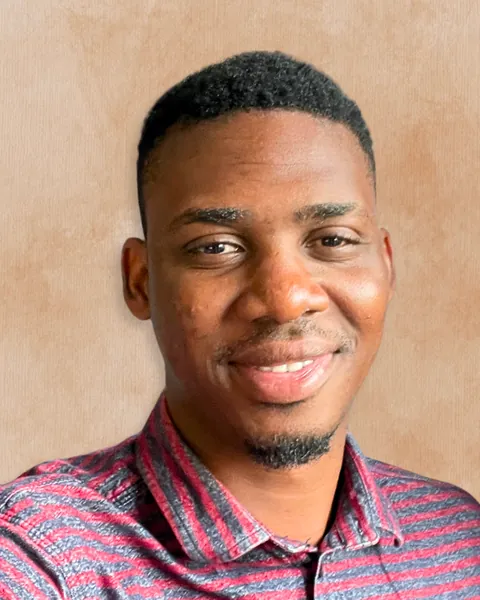 Maxwell Cofie from the shoulders up, smiling against a warm beige background